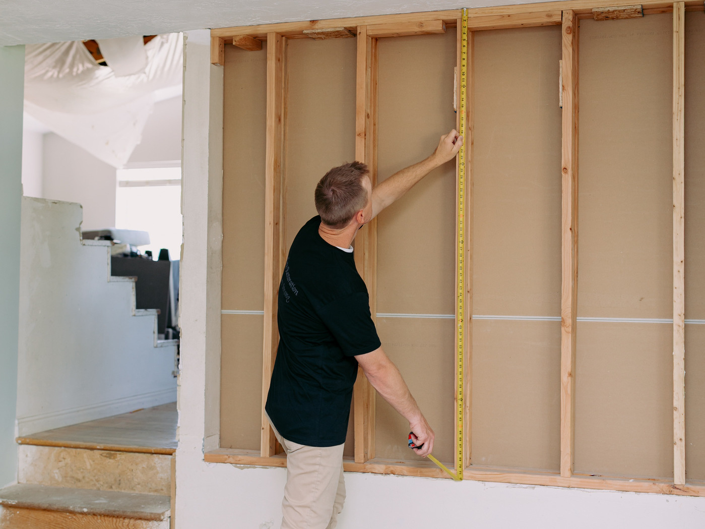 Carpenter framing interior walls during residential reconstruction after property damage